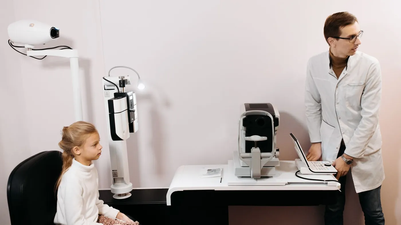 Oftalmólogo preparando un examen visual a una niña en la consulta